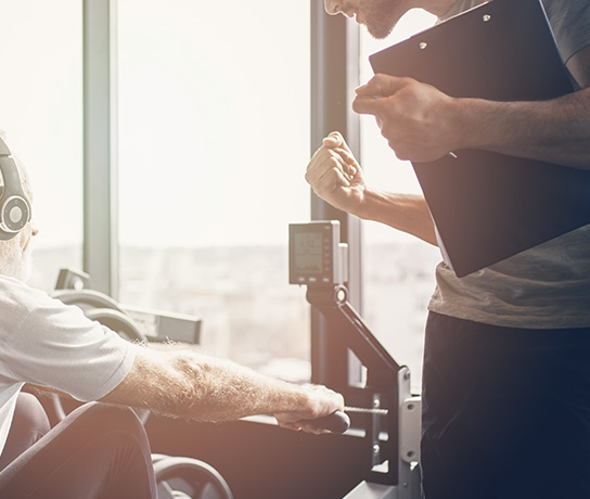 プライベートジムでトレーニングをサポートするトレーナーの男性｜健康維持や肩こり・腰痛予防・ボディメイク