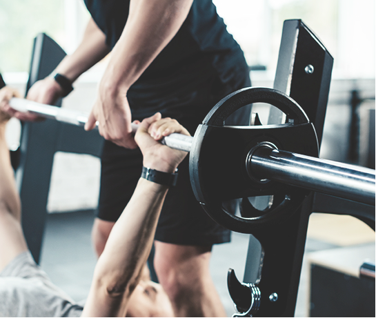 プライベートジムでトレーニングをサポートするトレーナーの男性｜健康維持や肩こり・腰痛予防・ボディメイク